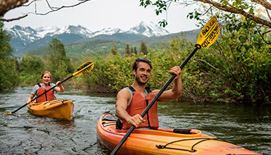 Two people in kayaks paddling down the River of Golden Dreams on a tour in Whistler