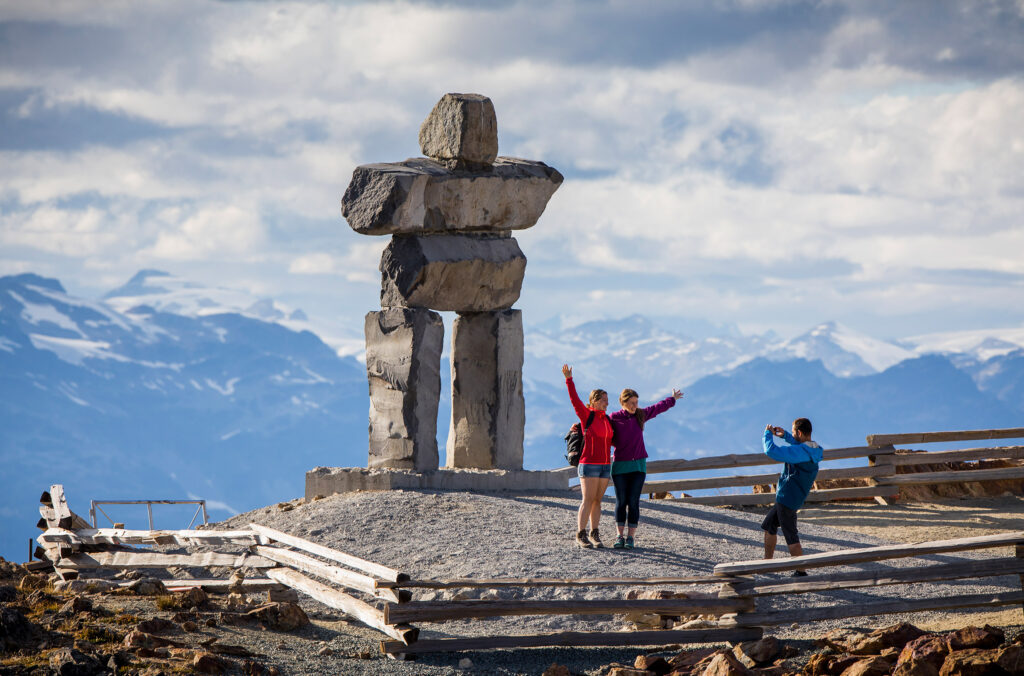Photos being taken in front of the Inuksuk at the top of Peak Chair on Whistler Mountain.
