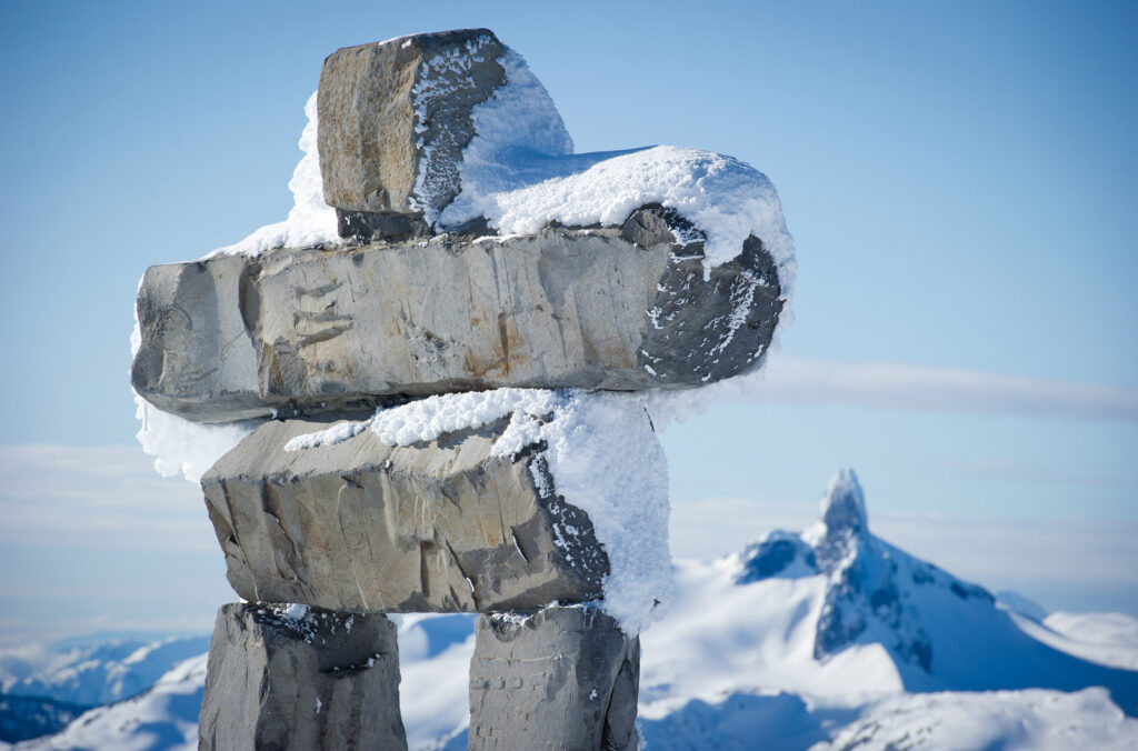 A snowy Inuksuk stands in the sunshine on a winter's day on Whistler Blackcomb.
