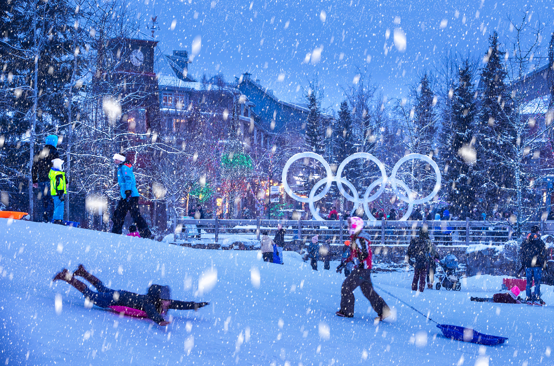 Snow falls as children sled at Whistler's Olympic Plaza.