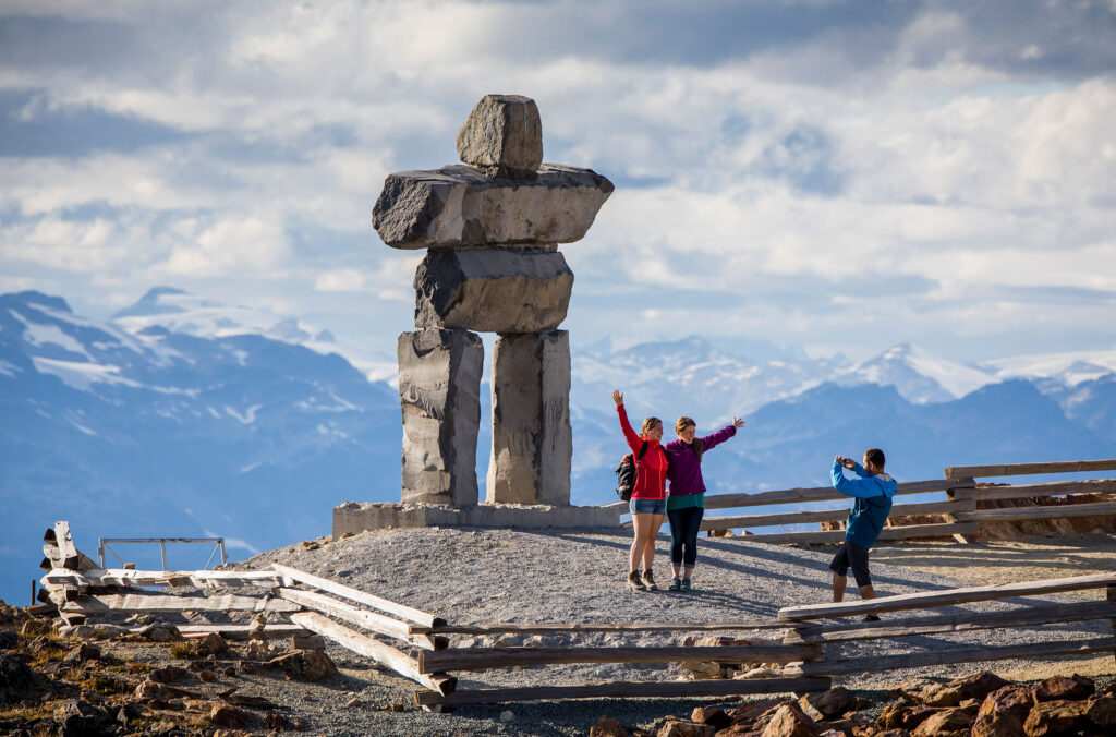 Hikers pose in front of the Inukshuk on Whistler Mountain in the summer.