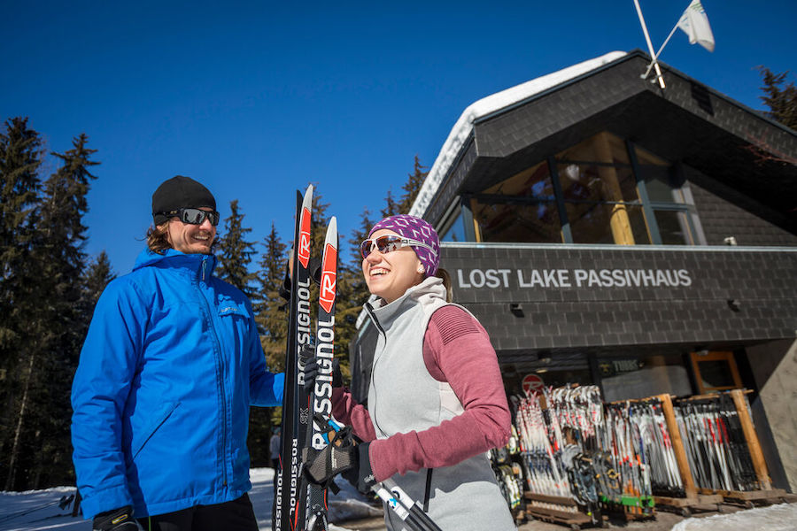 Two people prepare to ski at the Lost Lake Passivhaus in Whistler. 