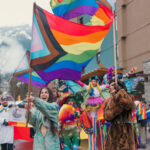 A colourful parade with rainbow flags flying as people celebrate the Whistler Ski and Pride Festival.