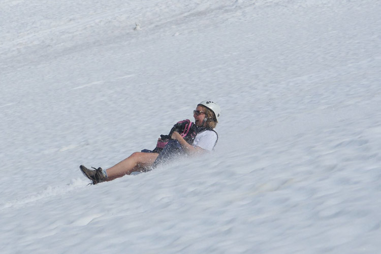 Women slides down Whistler Mountain glacier on a Glissade Tour