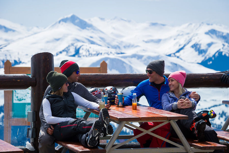 Four people sit down at a table for a ski break in the mountains in winter. 
