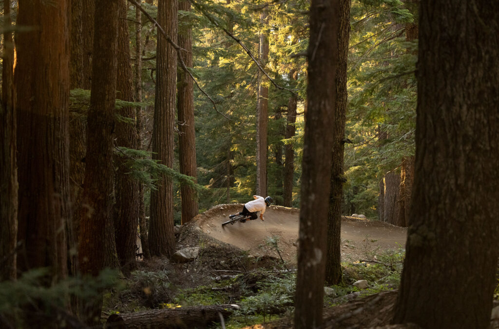 A lone downhill mountain biker rips around a berm in the Creekside Zone of the Whistler Mountain Bike Park.