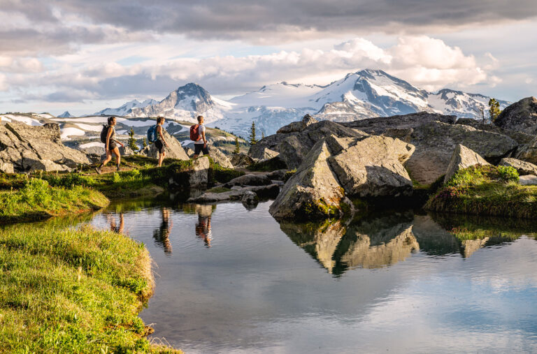Three hikers walk on the trail around the Decker Tarn on Blackcomb Mountain.