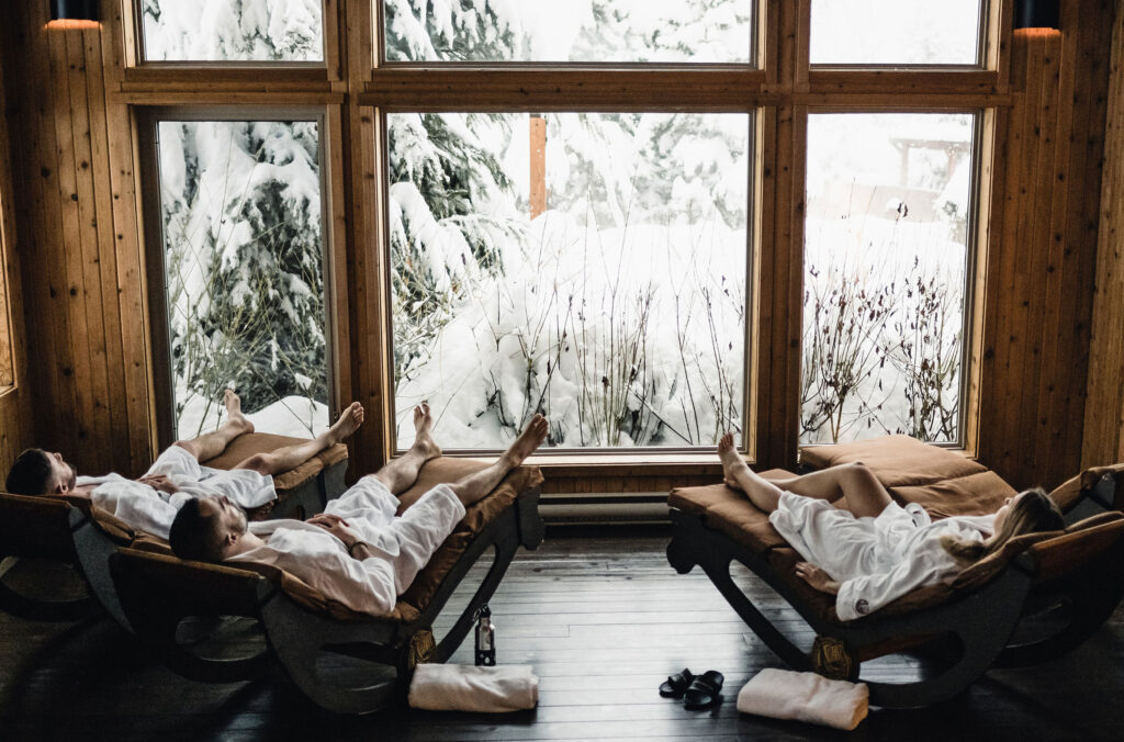 Three people relax in a solarium at the Scandinave Spa in Whistler.