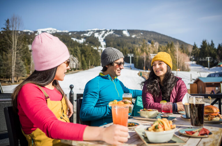 Three skiers relax in the sun enjoying Whistler apres.