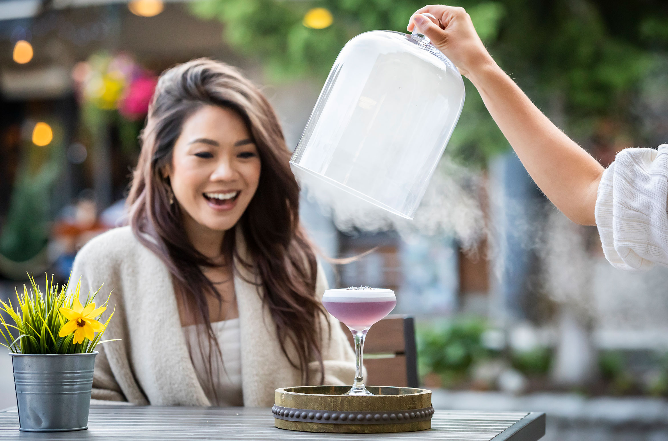 A woman is amazed by a smokey cocktail on the patio of Araxi in Whistler.