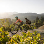 Two bike riders enjoy the Whistler Valley Trail around Green lake in the spring sun.