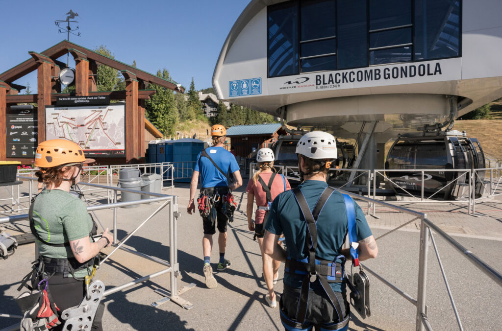 Three people get on the Blackcomb Gondola at the base of Blackcomb Mountain with a Ziptrek Ecotours guide. They're heading up to do the Sasquatch zipline.