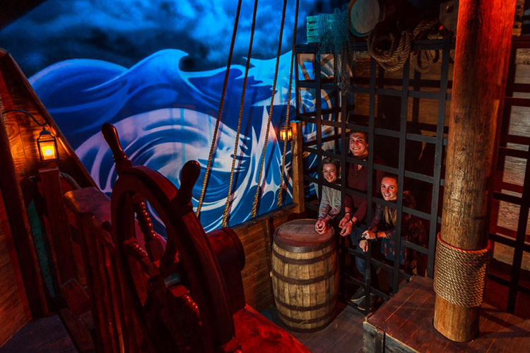 People locked in a cage in a pirate themed room.