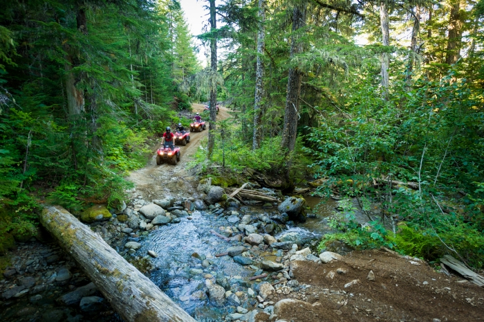 An ATV tour crossing a creek.