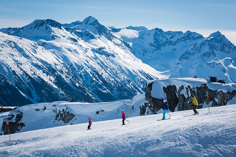 family skiing on a mountain top ridge