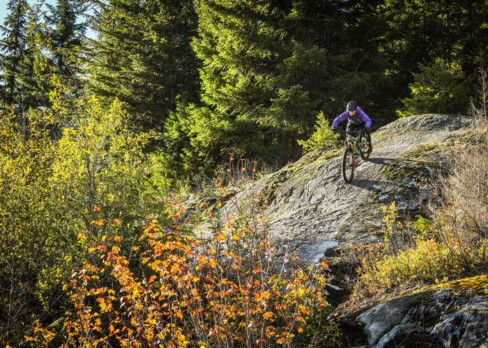 A mountain biker rides down a rock slab on the AC/DC trail, part of the Westside trail network.