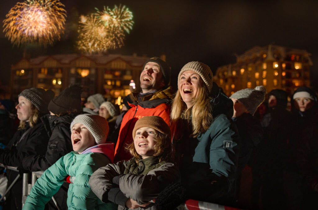 A family look up with excitement as they watch the Fire & Ice Show at the base of Whistler Mountain. 