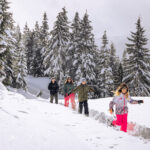 A family snowshoes in the Callaghan Valley at Whistler Olympic Park. The snow is deep and bright.