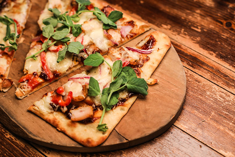 Slices of BBQ chicken pizza displayed on a wooden board.