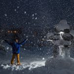 Person holding arms open to snowy sky in Whistler
