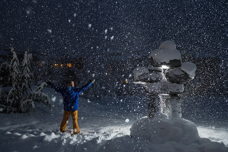 Person holding arms open to snowy sky in Whistler