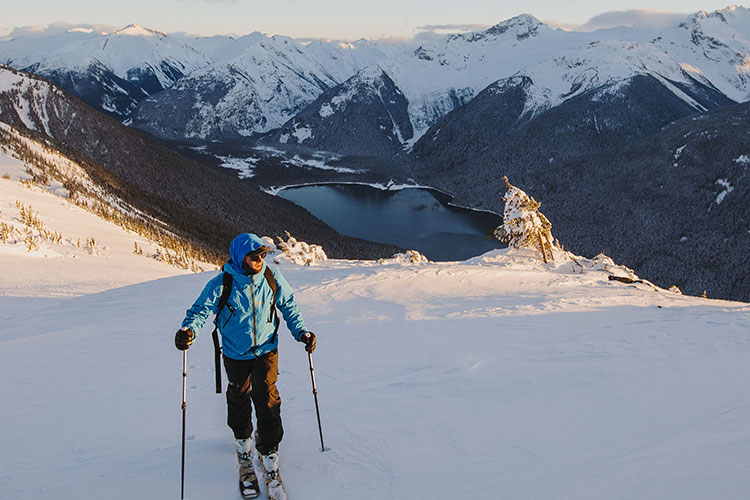 A skier looks over his shoulder at the scenery as he skins up the hill.