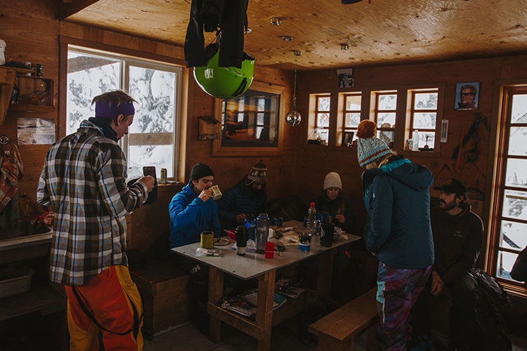 Friends inside a backcountry ski hut getting ready for the day ahead.