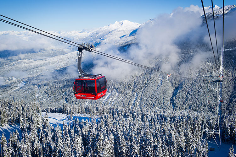 A red Peak 2 Peak Gondola cabin makes its way across the valley from Whistler to Blackcomb Mountain. 