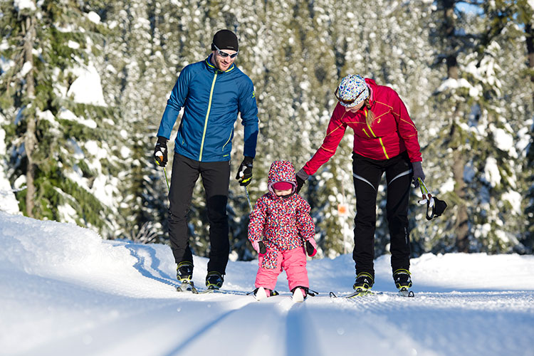 A family enjoy some Nordic skiing with their little one.