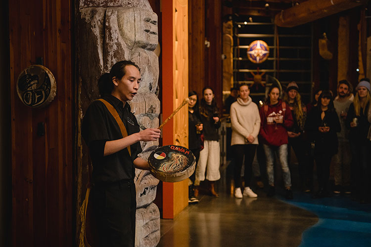 Redmonf beats a drum and sings to a crowd of people at the SLCC in Whistler.