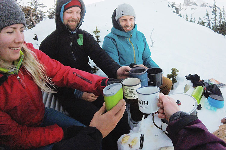 Backcountry skiers cheers with their morning coffees after a night on Black Tusk.
