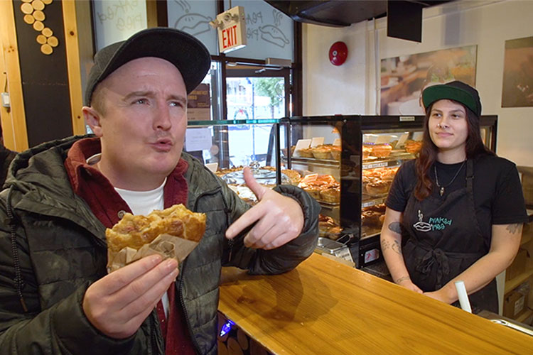 Man eats a meat pie while chatting to an Aussie about why she came to Whistler.