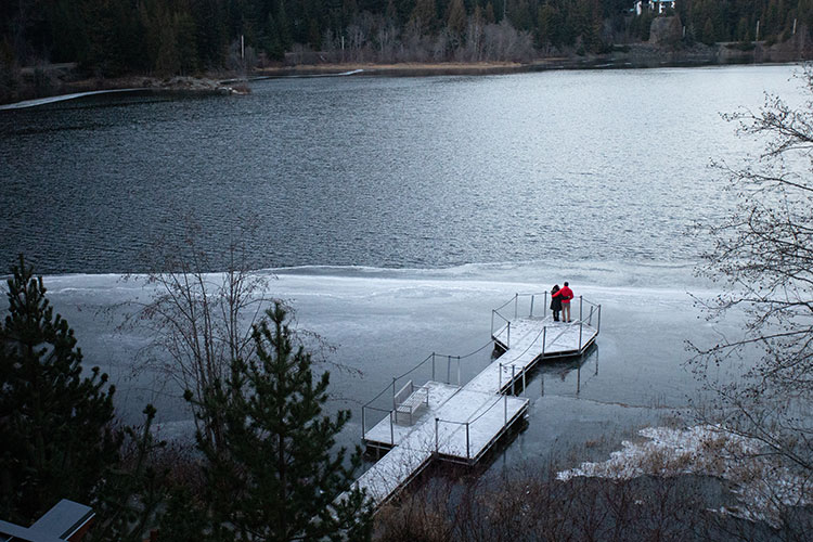 A couple are out on a dock on a lake enjoying the view.