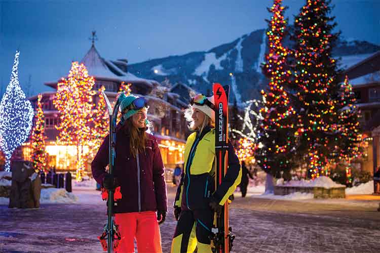 Women skiers on a lit village stroll.