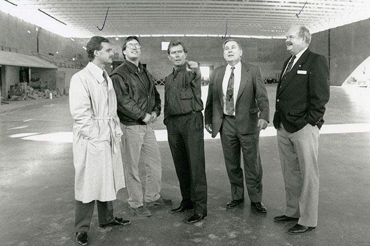 Four men stand on a half built hockey rink in Whistler.