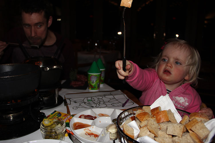 A child waves a long, fondue fork in the air.