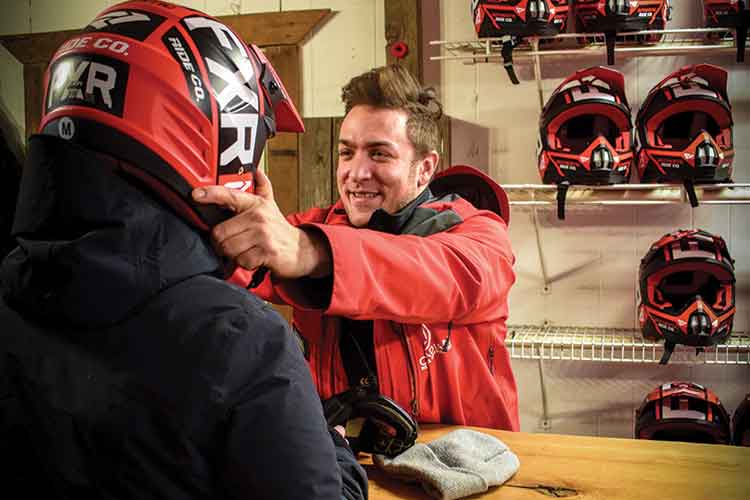 Rider getting fitted with a helmet for a snowmobile tour.