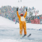 A skier makes his way across an icy pool at WSSF's Slush Cup. He's wearing a tiger onesie.