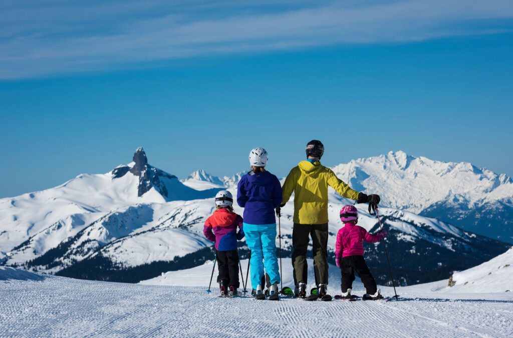 A family of skiers look out over Black Tusk in Whistler.