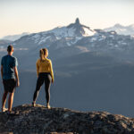 Two hikers look at the view from the top of Whistler Mountain out over to Black Task in the summer.