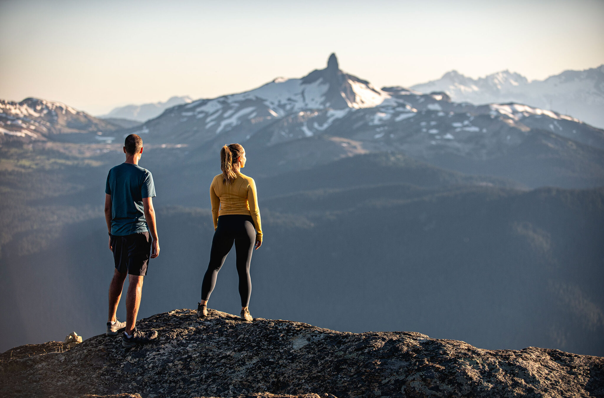 Two hikers look at the view from the top of Whistler Mountain out over to Black Task in the summer.