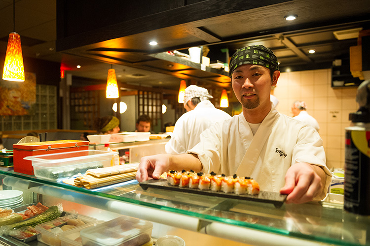 A Sushi Chef serving a roll at Sushi Village in Whistler