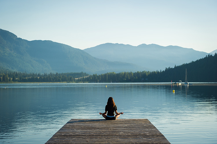 Woman meditating at a lake in Whistler