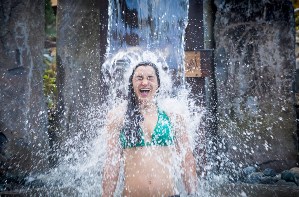 A woman stands under a cold waterfall at the Scandinave Spa Whistler.