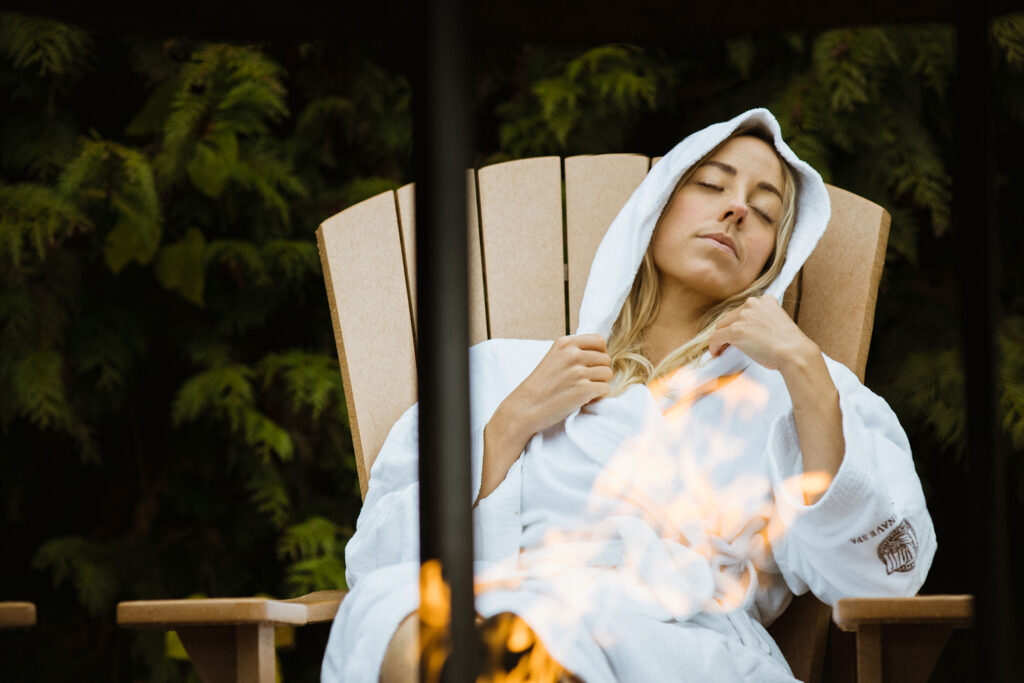 A woman relaxes in a chair by the fire at the Scandinave Spa in Whistler.