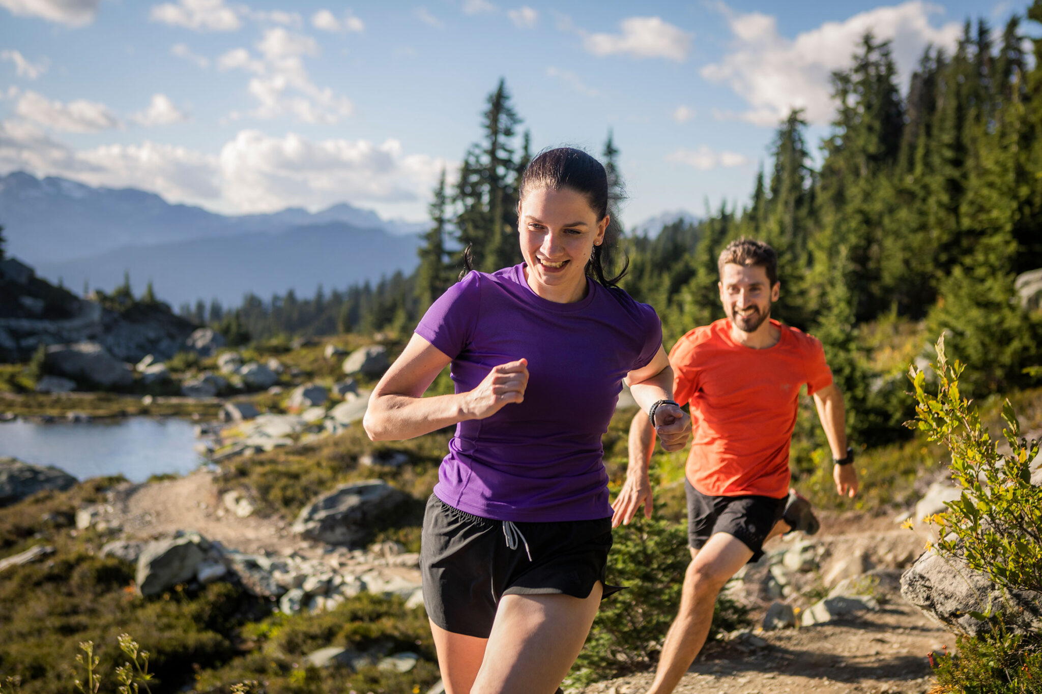 A man and woman trail run in the alpine in Whistler.