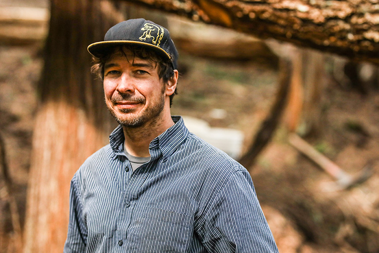 Dan Raymond smiling in front of a tree