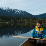 Kid paddling a canoe on a lake in Whistler
