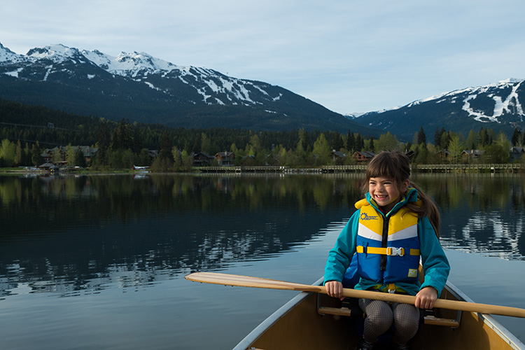 Kid paddling a canoe on a lake in Whistler