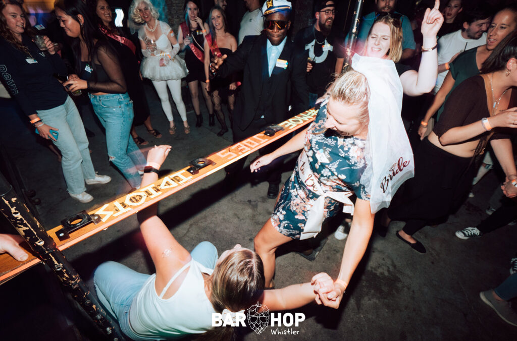 A bride-to-be attempts the limbo with a friend in a nightclub in Whistler.